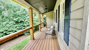 A covered porch with wooden flooring, a railing, and a view of a green landscape. - Charming 3-bedroom secluded house in Acworth (Acworth)