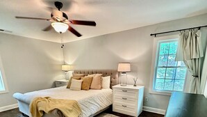 A bedroom with a bed, nightstands, a desk, a ceiling fan, and a window with curtains. - Charming 3-bedroom secluded house in Acworth (Acworth)