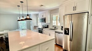 A modern kitchen with white cabinetry, stainless steel appliances, and pendant lighting. - Charming 3-bedroom secluded house in Acworth (Acworth)