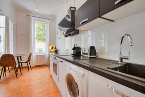Ett modernt kök med en inbyggd tvättmaskin, ett handfat och en matplats med stolar.