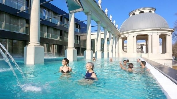 Ein Poolbereich mit klarem, blauen Wasser, umgeben von moderner Architektur und einer großen Kuppelkonstruktion.
