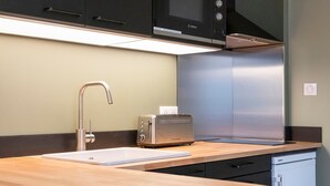 A modern kitchen with a built-in microwave, toaster, stainless steel refrigerator, and a wooden countertop. - La Cachette de Stanislas - Centre-ville de Nancy (Nancy)