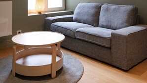A modern living room with a grey sofa, a round wooden table, and a floor lamp. - La Cachette de Stanislas - Centre-ville de Nancy (Nancy)