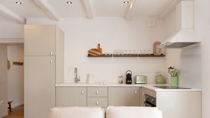 A modern kitchen with white cabinetry, a built-in oven, a coffee maker, and a toaster. - Le cosy de Keller - Nancy Centre (Nancy)