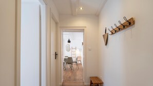 A hallway with wooden flooring, a bench, and a coat rack on the wall. - Le cosy de Keller - Nancy Centre (Nancy)
