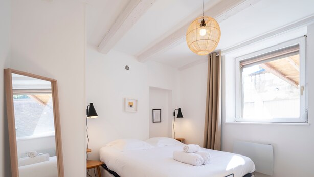 A neatly arranged bedroom with a large bed, bedside lamps, a mirror, and a window with curtains. - Le cosy de Keller - Nancy Centre (Nancy)
