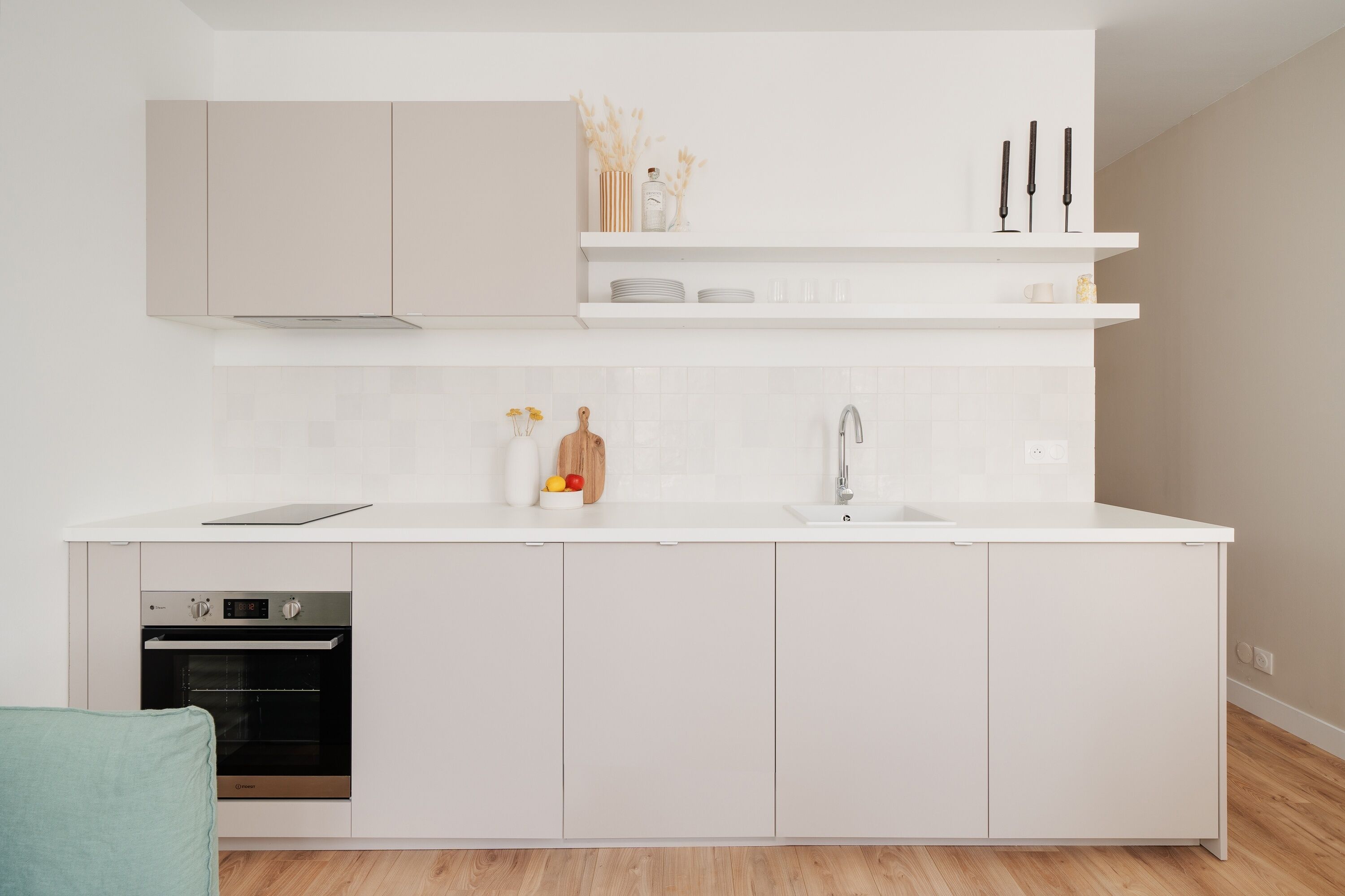 A modern kitchen with white cabinetry, a built-in oven, a sink, and a countertop with decorative items.