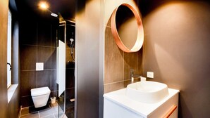 A modern bathroom with a white sink, a round mirror, and a toilet. - Le Cachet de la Craffe - Au cœur de Nancy (Nancy)