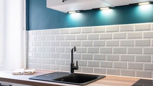 A modern kitchen with white cabinets, a black sink, and a teal backsplash. - L'Alerion Nancéien - Charme au coeur de Nancy (Nancy)