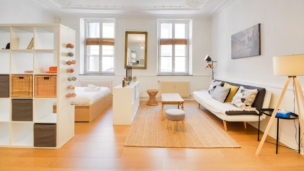 A modern living room with a sofa, a coffee table, a bookshelf, and a large window. - Le Cocon des Ponts - Studio 29 m² à Nancy (Nancy)