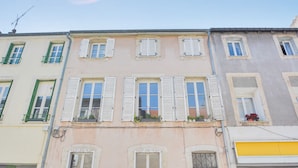 A row of multi-story buildings with white shutters, balconies with green railings, and a clear blue sky. - Le Cocon des Ponts - Studio 29 m² à Nancy (Nancy)