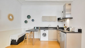 A compact kitchen with a washing machine, a sink, and a stove. - Le Cocon des Ponts - Studio 29 m² à Nancy (Nancy)