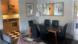 A modern kitchen with wooden cabinets and a built-in oven, a dining area with a black table and chairs, and a large mirror on the wall. - Delightful Howth Village apartment in Dublin (Dublin)