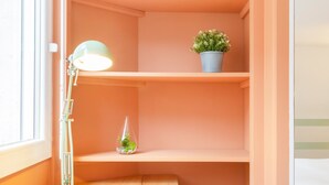 A workspace with a wooden desk, a zebra-patterned chair, a green desk lamp, and shelves with potted plants.
