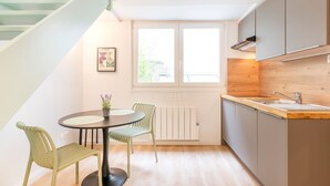 A modern kitchen with a dining area, featuring a staircase, a window with a view, and a radiator.