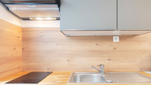 A modern kitchen with a wooden countertop, stainless steel sink, and a built-in stove.