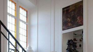A staircase with black railings and a white wall with a painting and a sculpture.