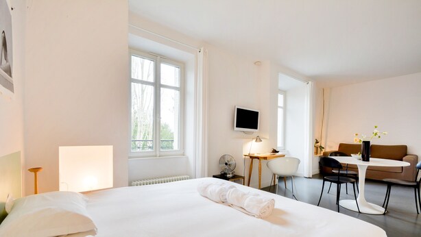 A hotel room with a large bed, a desk, a chair, a TV, and a small table with a lamp. - L'Hôtel Particulier - L'appartement de Nicole (Nancy)