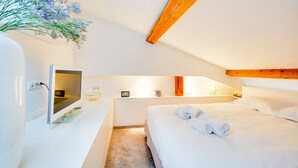 A modern hotel room with a large bed, a bedside table, a flat-screen TV, and a vase with flowers. - L'Hôtel Particulier - L'appartement de Pierre (Nancy)