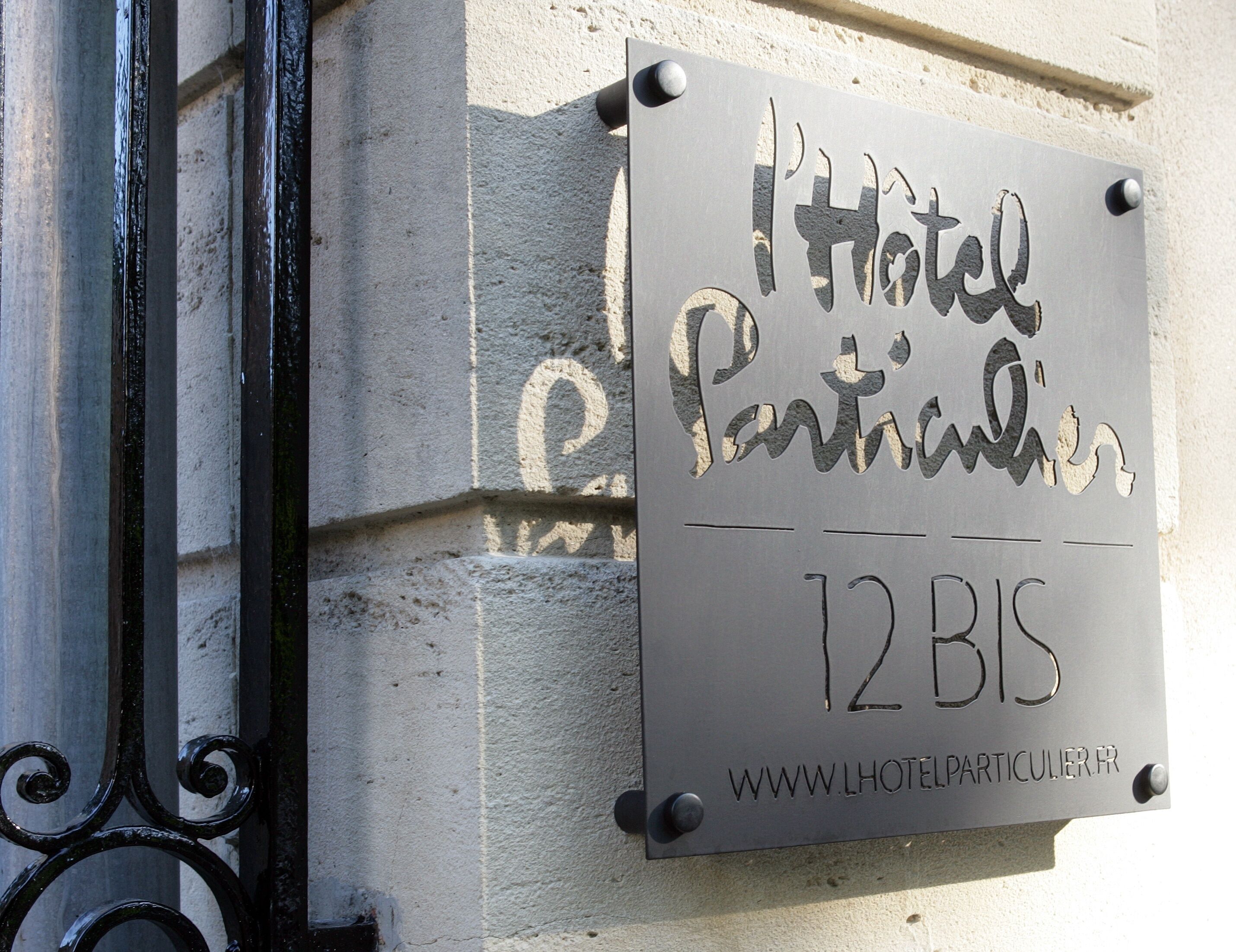 Señal de hotel con el nombre 'Hotel Particulier' y la dirección '12 BIS'.