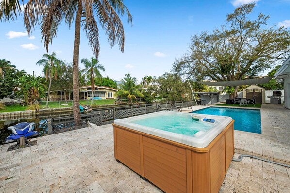 A hot tub in a backyard with a pool, surrounded by palm trees and a fence. - Uhost AI Miami 5BR Heated Pool Hot Tub (Aventura)