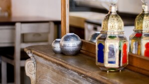 A wooden counter with decorative glass bottles and a mirror reflecting a kitchen area. - Le cocon des Deux Sirènes - Studio cosy pour 2 à Nancy (Nancy)
