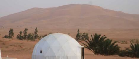 A dome-shaped structure in a desert landscape with a mountain in the background.