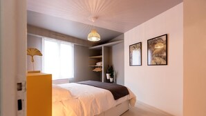 A bedroom with a bed, bedside table, wardrobe, and a hanging light fixture. - Le Coquet de Simon - Proche de la place Stanislas (Nancy)