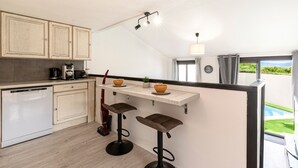 Eine kompakte Küche mit Geschirrspüler, Kaffeemaschine und einer kleinen Kücheninsel mit Hockern.