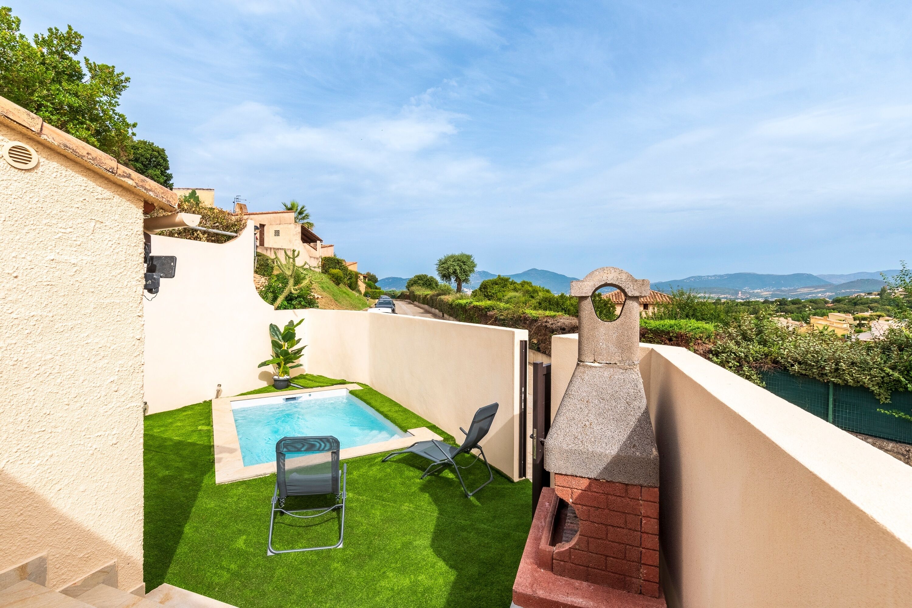 Una terraza en la azotea con piscina, zona de barbacoa y vistas del paisaje circundante.