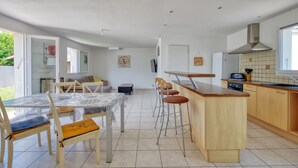 Une cuisine moderne dotée d’un îlot central, de tabourets de bar et d’une table à manger avec des chaises.