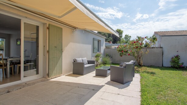 Une terrasse avec des meubles d’extérieur, un espace abrité et une vue sur le jardin arrière.