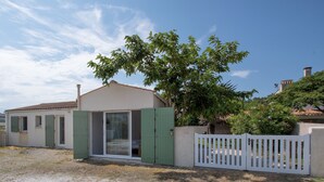 Une maison avec une porte-fenêtre coulissante, une clôture blanche et un arbre dans le jardin.