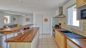 Une cuisine moderne dotée d’un plan de travail en bois, d’appareils électroménagers en acier inoxydable et d’une fenêtre laissant entrer la lumière naturelle.