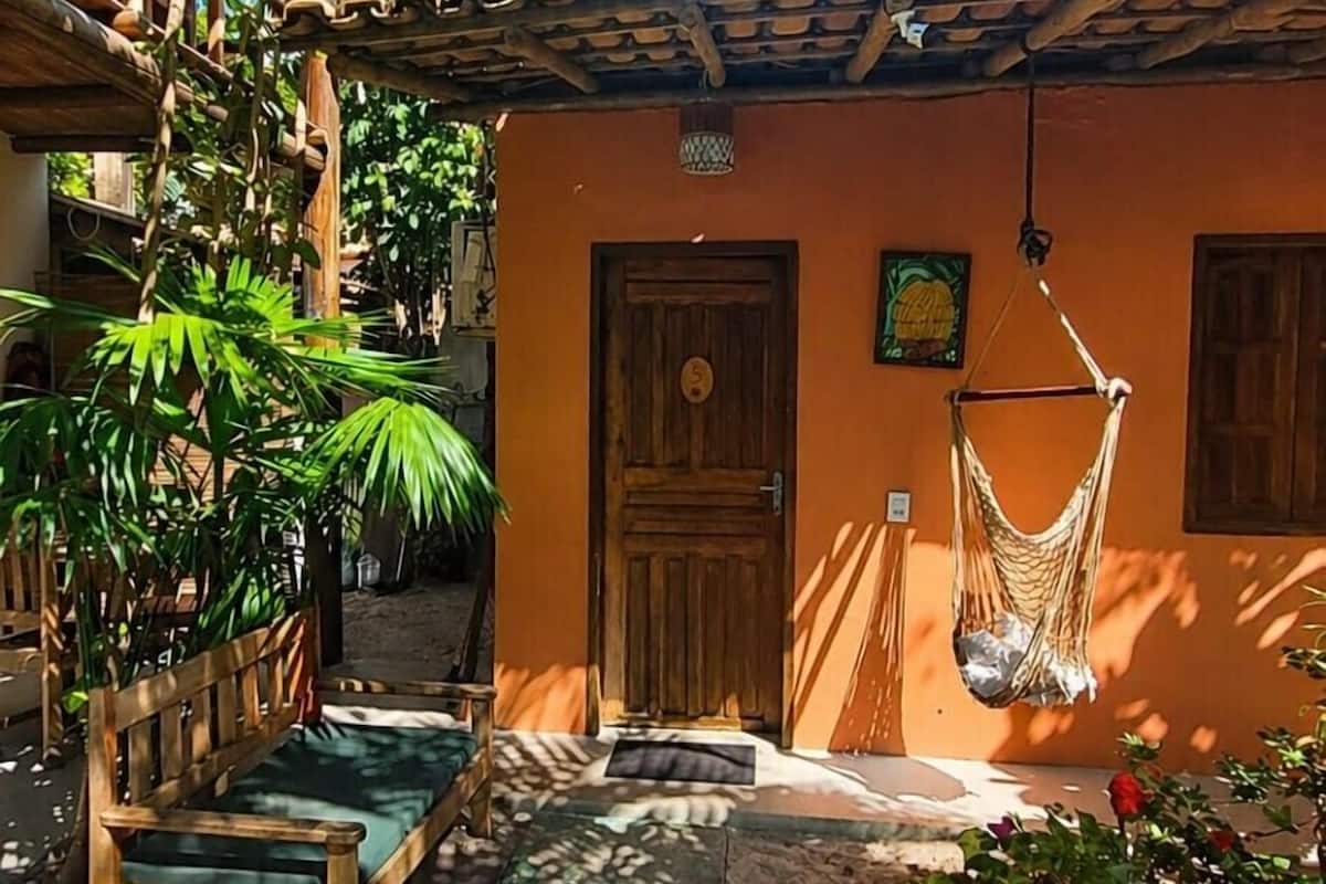 A wooden bench, a hammock, and a door with a number plate.