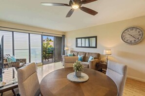 Un salon moderne avec une table ronde, deux canapés, un ventilateur de plafond et une grande horloge murale.