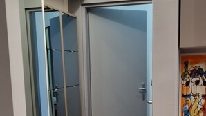 A hallway with a wooden floor, a sliding door, and a mirror reflecting a room with a door. - Cozy 1-bedroom apartment in fantastic Milano with AC, WiFi (Milano)
