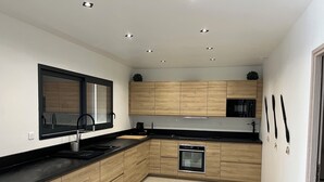 Eine moderne Küche mit Holzschränken, einem eingebauten Backofen und einer schwarzen Arbeitsplatte.
