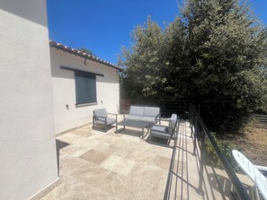 A patio area with a white wall, a window, and a sofa.
