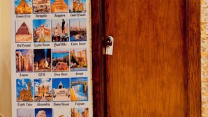 A hotel room with a wooden door marked "403" and a poster on the wall listing daily tour options like the Pyramids of Giza, Egyptian Museum, and Cairo Tower. - Flower Pyramids Inn (Giza)