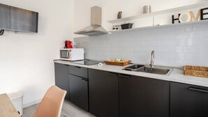 Eine moderne Küche mit dunklen Schränken, einer weißen Arbeitsplatte, einer Mikrowelle, einem Spülbecken und einer Dunstabzugshaube.