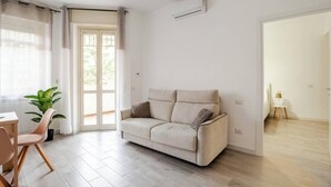 Ein Wohnzimmer mit einem beigen Sofa, einem Holztisch und einem Blumentopf.