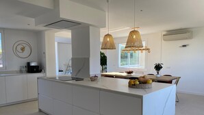A modern kitchen with a central island, pendant lighting, and a view of the outdoors. - Sea views, located 600 meters from the beach.  Garden, pool, and A/C. (Sa Riera)