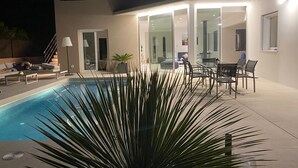 A modern house with a swimming pool, outdoor seating, and a glass-enclosed patio area. - Sea views, located 600 meters from the beach.  Garden, pool, and A/C. (Sa Riera)