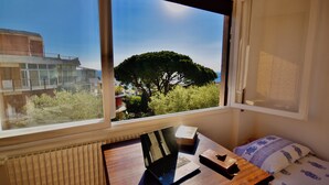 Una stanza con vista su un albero e un edificio attraverso una finestra.