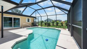 Une piscine dotée d’une enceinte en verre, entourée d’un espace patio.