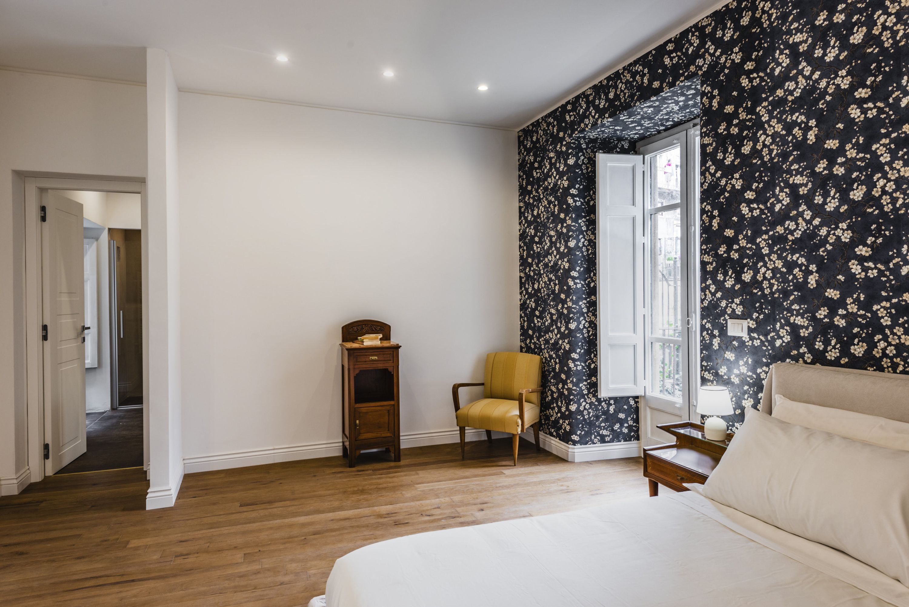 Une chambre à coucher avec un grand lit, une chaise, une table de chevet et une fenêtre donnant sur un beau paysage.