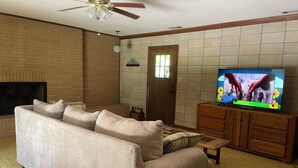 Un saló amb un sofà beix, un armari de fusta i una televisió.