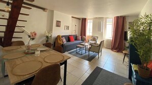 A spacious living area with a dining table, sofa, and a staircase.