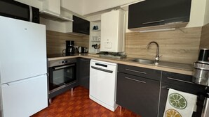 A modern kitchen with white and black cabinetry, stainless steel appliances, and a wooden floor.